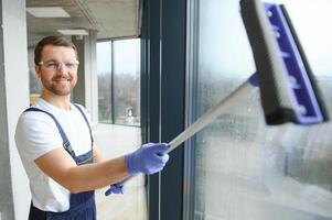 een werknemer van een professioneel schoonmaak onderhoud wast de glas van de ramen van de gebouw. vitrine schoonmaak voor winkels en ondernemingen. foto