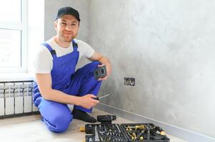 bouw arbeider elektricien assembleert een elektrisch stopcontact in een appartement foto