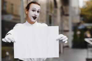 uw tekst hier. acteur mime Holding leeg wit brief. kleurrijk portret met grijs achtergrond. april dwazen dag foto