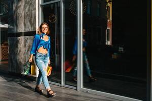 glimlachen jong vrouw poseren met een handvol van boodschappen doen Tassen. boodschappen doen concept. foto