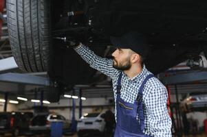 portret van een monteur repareren een opgeheven auto foto