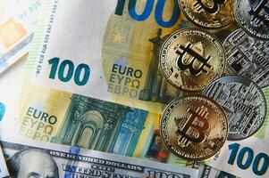 dichtbij omhoog hoop van gouden bitcoin fysiek munten Aan top van euro, dollar bankbiljetten achtergrond, hoog hoek visie, selectief focus foto