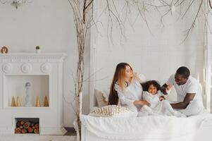 opgewonden multiraciaal jong familie met weinig meisje kind hebben plezier, dolblij gelukkig. Internationale mam en vader Speel met klein meisje, genieten weekend Bij huis samen foto