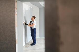 arbeider schilder verven een muur. professioneel bouwer maakt reparaties. foto