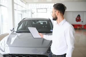 lachend, vriendelijk auto verkoper staand in auto salon. foto