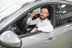 ja, dat is mijn nieuw auto. klant in auto dealerschap. jong Mens met sleutels in hand- foto