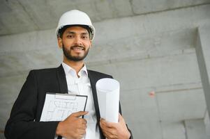 Aziatisch ingenieur staand Aan plaats bouw posten zelfverzekerd , ingenieur bouw gelukkig baan succes met in doelwit planning foto