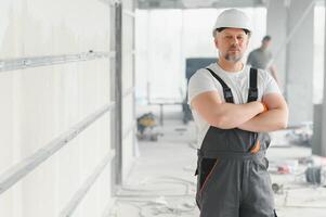 Mens bouwer. architect is staand in gebouw. portret van denken bouwer. bouwer architect in onvoltooid gebouw. architect in werken uniform. foto