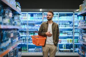 jong Mens buying boodschappen Bij de supermarkt. andere klanten in achtergrond. consumentisme concept. foto