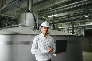 glimlachen en gelukkig medewerker. industrieel arbeider binnenshuis in fabriek. jong technicus met wit moeilijk hoed. foto