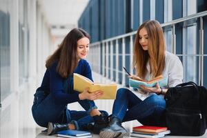 vrouw studenten zittend Aan de verdieping en lezing aantekeningen voordat tentamen foto