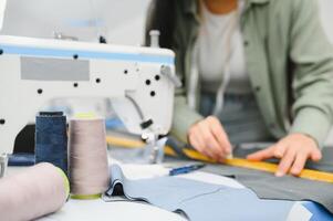 positief jong vrouw naaien met professioneel machine Bij werkplaats. foto