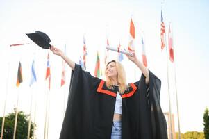 gelukkig Universiteit afstuderen meisje. de meisje is staand in de buurt de Universiteit tegen de achtergrond van de vlaggen van verschillend landen. de concept van Internationale onderwijs. foto