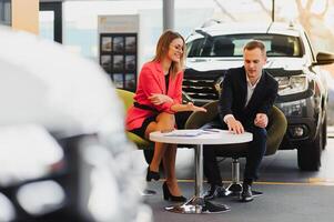 mooi jong vrouw koopt een auto in de handel salon. foto