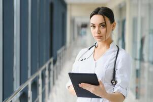 portret van jong vrouw dokter staand in ziekenhuis hal. Kaukasisch vrouw werken in verpleging huis. foto