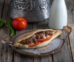 tikka belegd broodje geserveerd in een schotel kant visie Aan houten tafel achtergrond foto