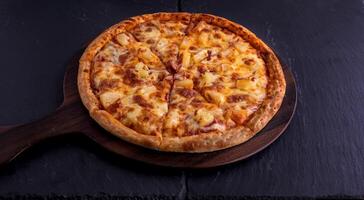 hawaiiaans pizza geïsoleerd Aan snijdend bord top visie Aan donker achtergrond Italiaans snel voedsel foto