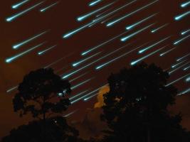 meteoor op de nachtelijke hemel donkeroranje wolk en boom in tropisch bos foto