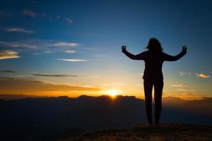 meisje in yogameditatie bovenop een berg bij zonsondergang foto