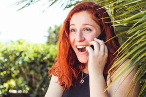 close-up van verrassingsmeisje met roodharige die op mobiele telefoon praat terwijl ze buiten staat foto