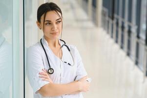 portret van jong vrouw dokter staand in ziekenhuis hal. Kaukasisch vrouw werken in verpleging huis. foto