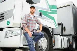 trots professioneel vrachtwagenchauffeur staand in voorkant van zijn vrachtwagen. vrachtvervoer en vervoer thema. foto