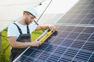 Mens ingenieur in uniform werken Aan zonne- panelen macht boerderij. zonne- paneel veld. schoon energie productie. groen energie. foto