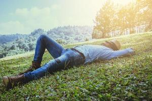 aziatische man reizen ontspannen in de vakantie. slapen ontspannen op het grasveld op de berg. in Thailand foto