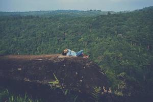 aziatische man reizen ontspannen in de vakantie. slapen ontspannen boeken lezen op rotsachtige kliffen. op de berg. in Thailand foto