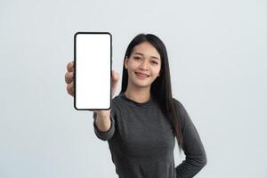 een vrouw is Holding een cel telefoon met een wit achtergrond. ze is glimlachen en ze is gelukkig. geïsoleerd Aan wit achtergrond. foto
