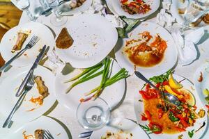 de overgebleven voedsel en vuil gerechten Aan de restaurant tafel. kladjes links over- na de feest. foto