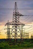 elektriciteit pylonen lager de macht levering aan de overkant een landelijk landschap gedurende zonsondergang. selectief focus. foto