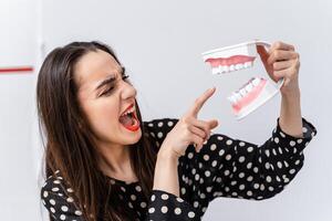 vrouw Holding leerzaam model- van mondeling holte met tanden Aan wit achtergrond. grappig emoties en uitdrukkingen. foto