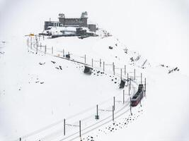 antenne visie van rood en wit trein in besneeuwd Zermatt, Zwitserland landschap foto