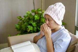 Aziatisch vrouw met kanker, ze hoest terwijl zittend met een boek naar verlichten spanning foto