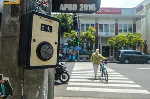 een zebra kruispunt uitgerust met verkeer lichten shows een vrouw fietser kruispunt de weg, Indonesië, 2 maart 2024. foto