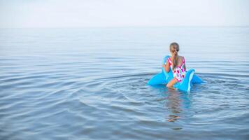 gelukkig meisje van Europese uiterlijk leeftijd van 7 zwemmen Aan een opblaasbaar groot haai speelgoed- in de zee.familie zomer roeping concept. kopiëren spatie.terug visie . foto
