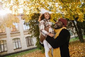 zwarte meid die plezier heeft en op de nek van zijn grootvader zit in het herfstpark foto