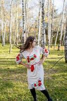 mooie vrouw in Oekraïense nationale traditionele kostuumkleren die in bos dansen foto