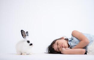 glimlachen weinig meisje en met hun geliefde pluizig konijn, presentatie van de schoonheid van vriendschap tussen mensen en dieren foto