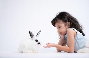 glimlachen weinig meisje en met hun geliefde pluizig konijn, presentatie van de schoonheid van vriendschap tussen mensen en dieren foto