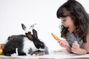 glimlachen weinig meisje en met hun geliefde pluizig konijn, presentatie van de schoonheid van vriendschap tussen mensen en dieren foto