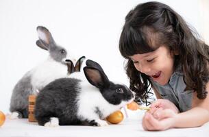 glimlachen weinig meisje en met hun geliefde pluizig konijn, presentatie van de schoonheid van vriendschap tussen mensen en dieren foto