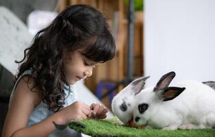 glimlachen weinig meisje en met hun geliefde pluizig konijn, presentatie van de schoonheid van vriendschap tussen mensen en dieren foto