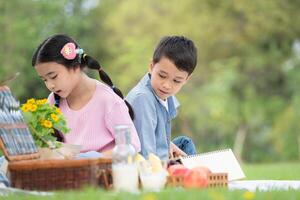 gelukkig familie genieten van een picknick in de park, kinderen zittend terug naar terug en lezing boeken. foto