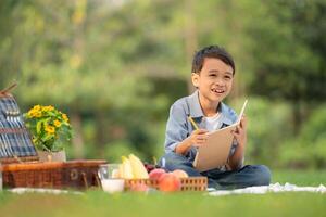 gelukkig familie genieten van een picknick in de park, jongen zittend en lezing boeken. foto