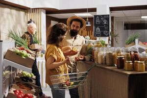 Mens en vrouw buying producten in nul verspilling op te slaan ontworpen naar minimaliseren plastic gebruik, creëren positief milieu invloed. klanten op zoek voor voedzaam etisch afkomstig boodschappen foto