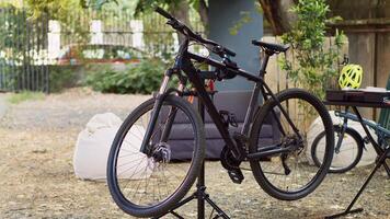 in tuin, fiets geplaatst Aan reparatiestandaard klaar voor nauwkeurig examen en corrigeren van gebroken componenten. buitenshuis zomer fiets onderhoud met professioneel apparatuur. foto