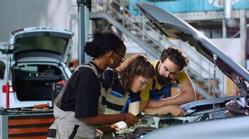 team van reparateurs in auto onderhoud gebruik makend van inspectie lamp naar fix opgepakt auto. collega's onderhoud gebroken voertuig, controle voor uit van bestellen transmissie gebruik makend van professioneel gereedschap foto