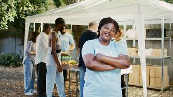 Afrikaanse Amerikaans vrouw vrijwilliger grijnst en poses gedurende een voedsel rit liefdadigheid evenement. humanitair steun programma dat biedt honger Verlichting en helpen naar de dakloos en de arm. portret schot. foto